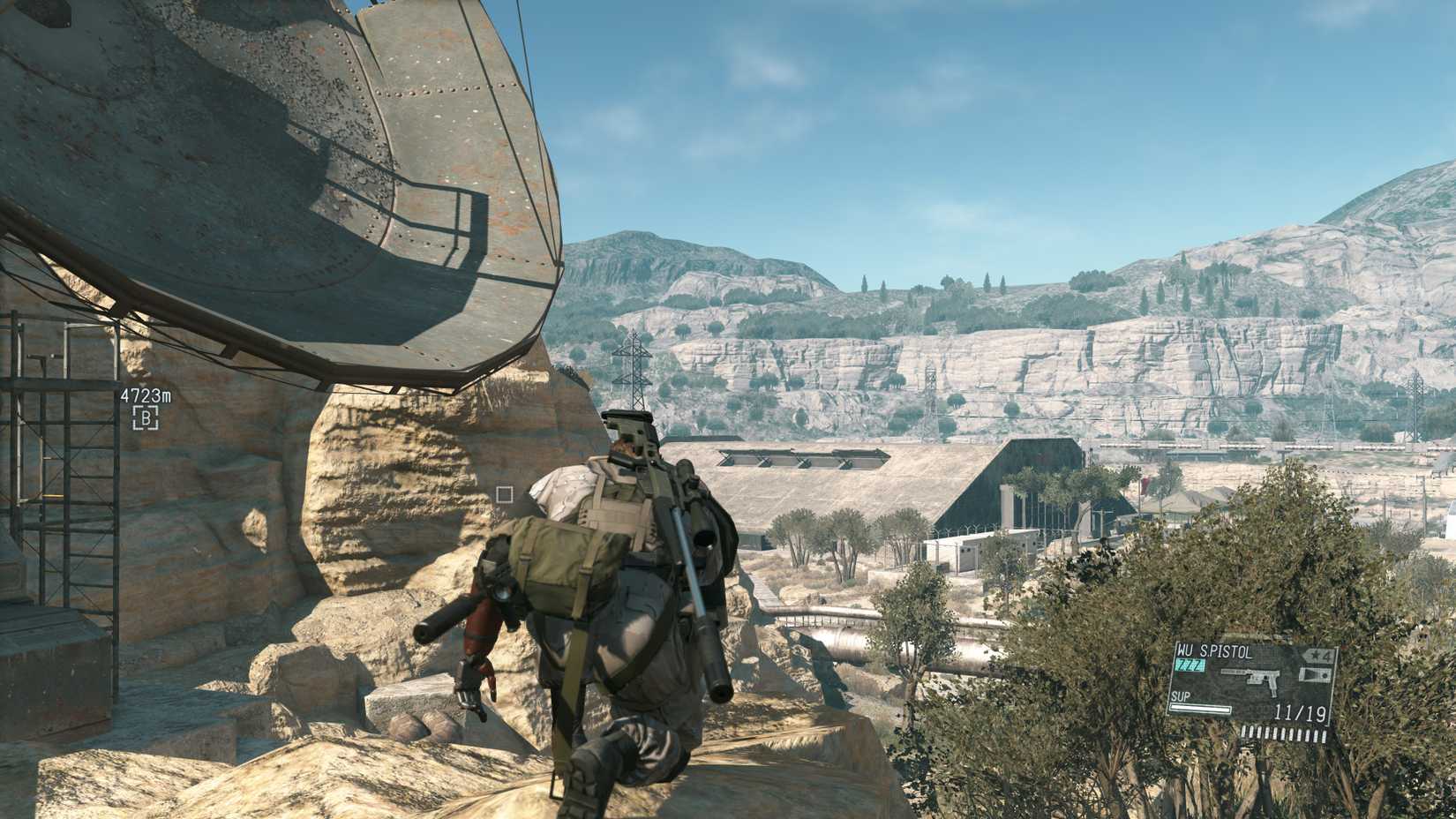 Snake crouches in the desert next to a satellite dish in Metal Gear Solid 5: The Phantom Pain.