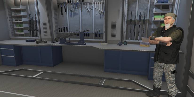 Mechanic standing beside a wall and shelf of weapons in GTA Online