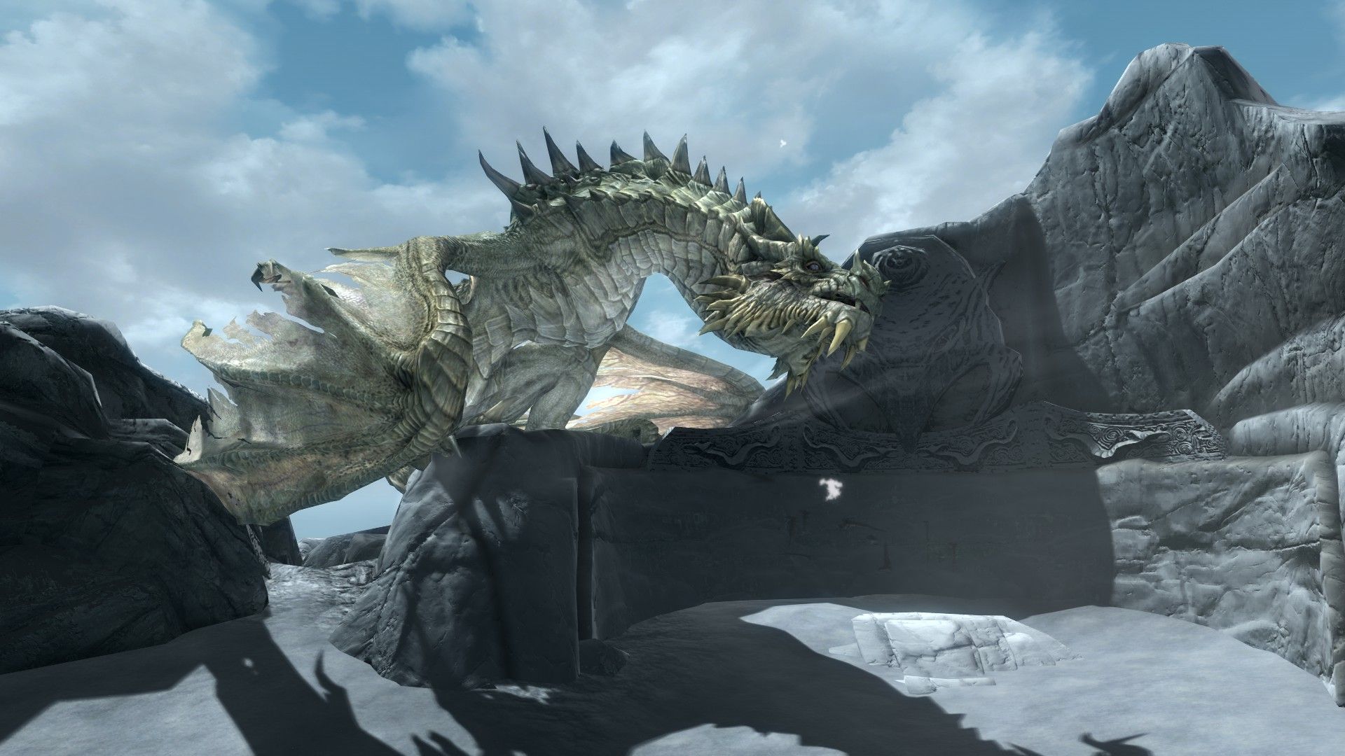 A dragon looks down at a mortal atop an ancient stone wall in Skyrim.