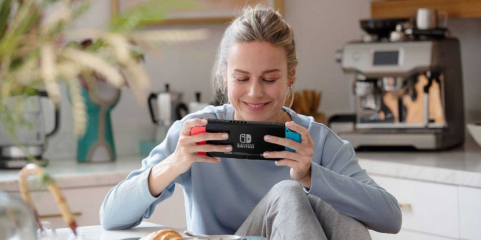 Brie Larson sitting down with a Nintendo Switch and smiling 
