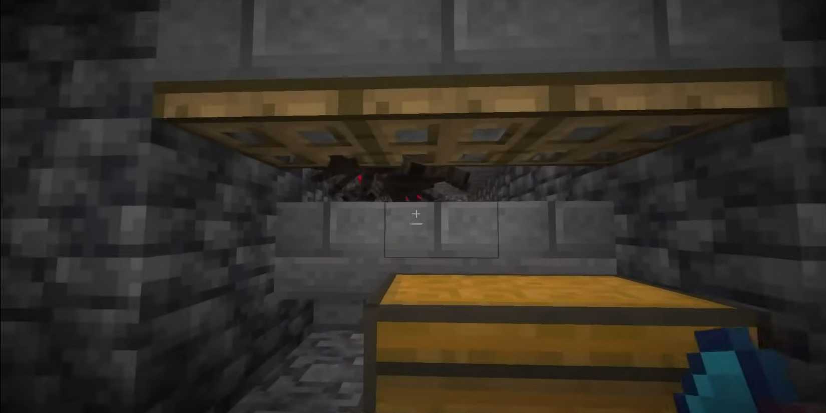 A stone room with a tunnel of spiders that cannot move towards the player. In Minecraft, there is a chest in front.
