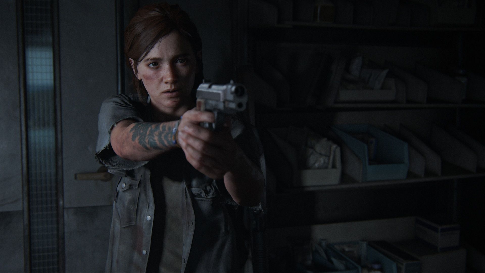Ellie Williams pointing her pistol at someone off camera with a serious expression on her face in The Last of Us Part 2.