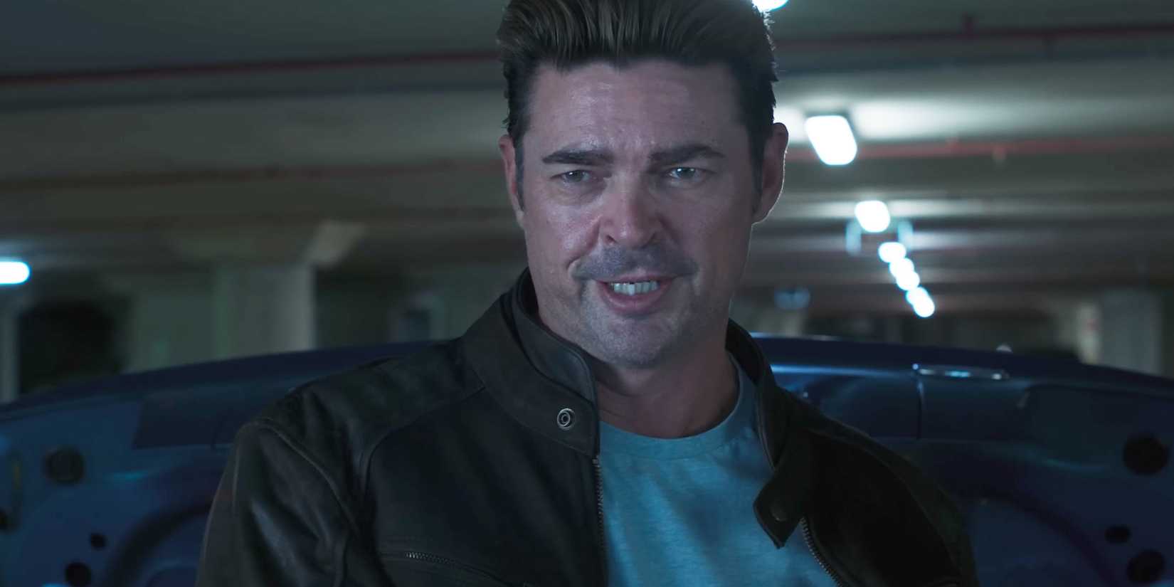 Karl Urban, who plays Johnny Cage, stands in the parking lot next to his car.