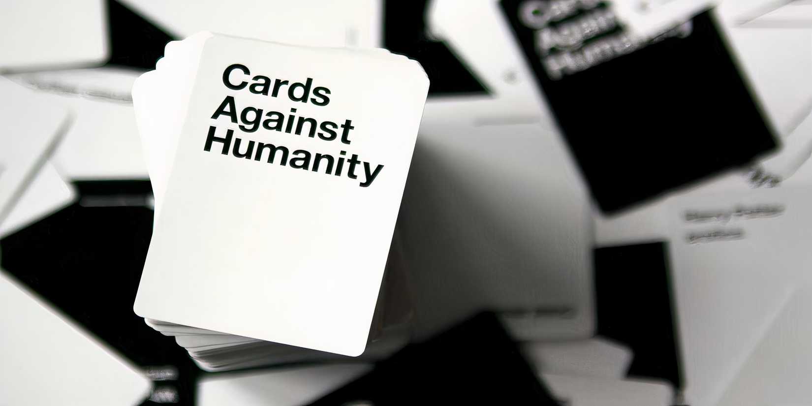A card against humanity card tires, sits on top of a table with black and white playing cards.