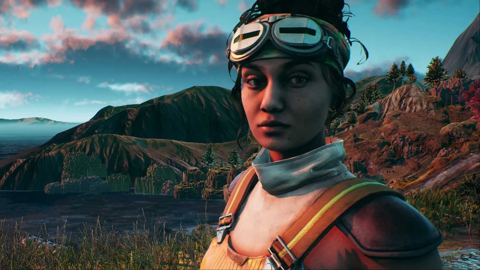 Parvati Holcomb standing in front of a lake with mountains in the background of the outer world.