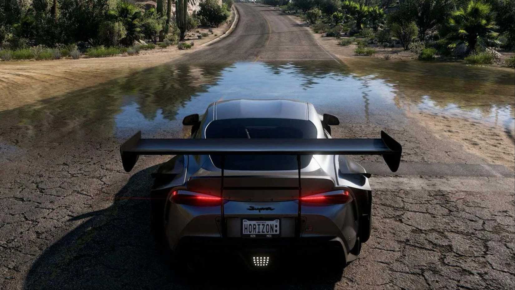A Toyota GR Supra driving through a shallow puddle on an empty road in Forza Horizon 5.