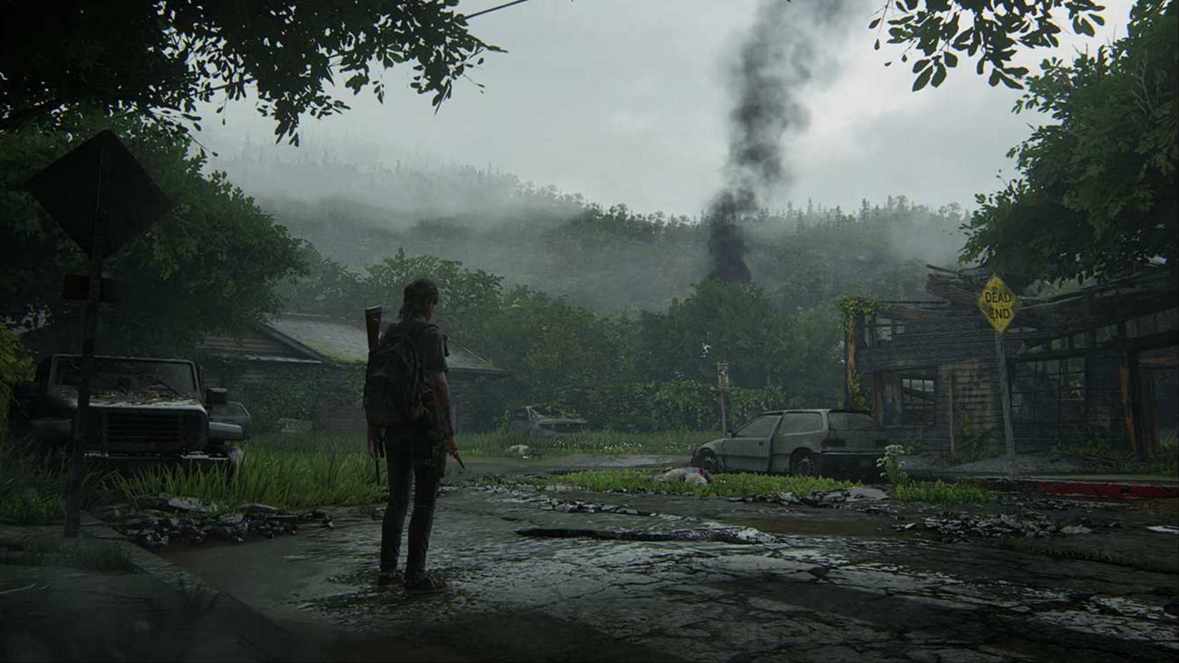 Ellie standing in the middle of an abandoned and lonely street with a smoke signal in the distance in The Last of Us: Part 2.