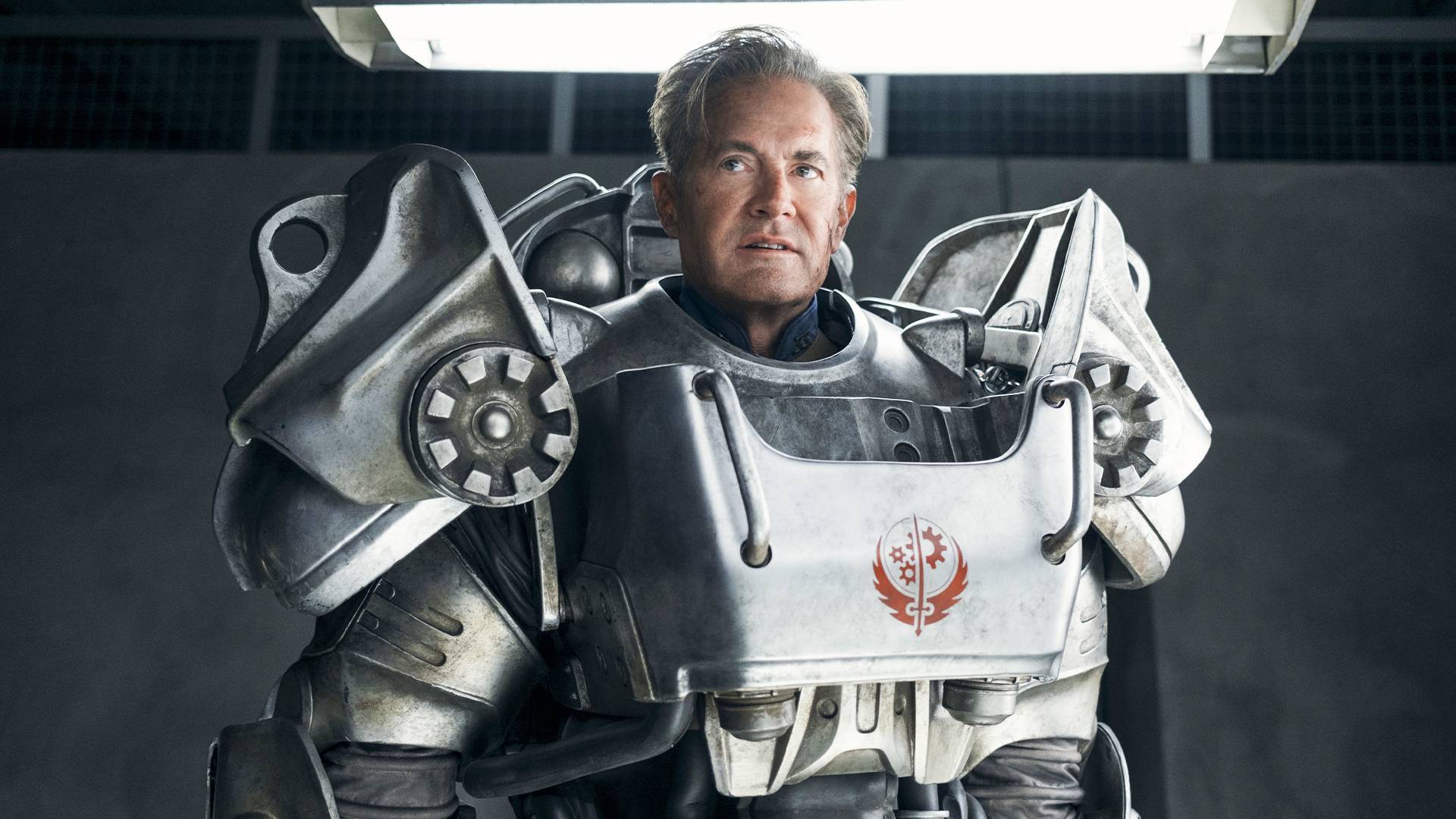 Fallout TV Show Hank in power armour standing in front of a grey wall.