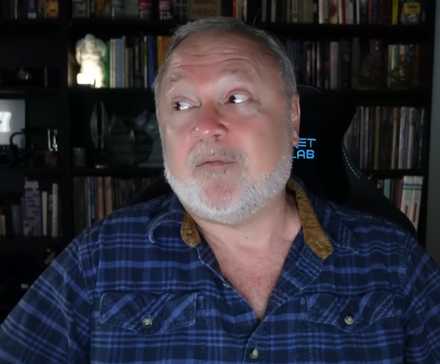 Tim Cain sat in a Secret Lab chair in front of a bookshelf.
