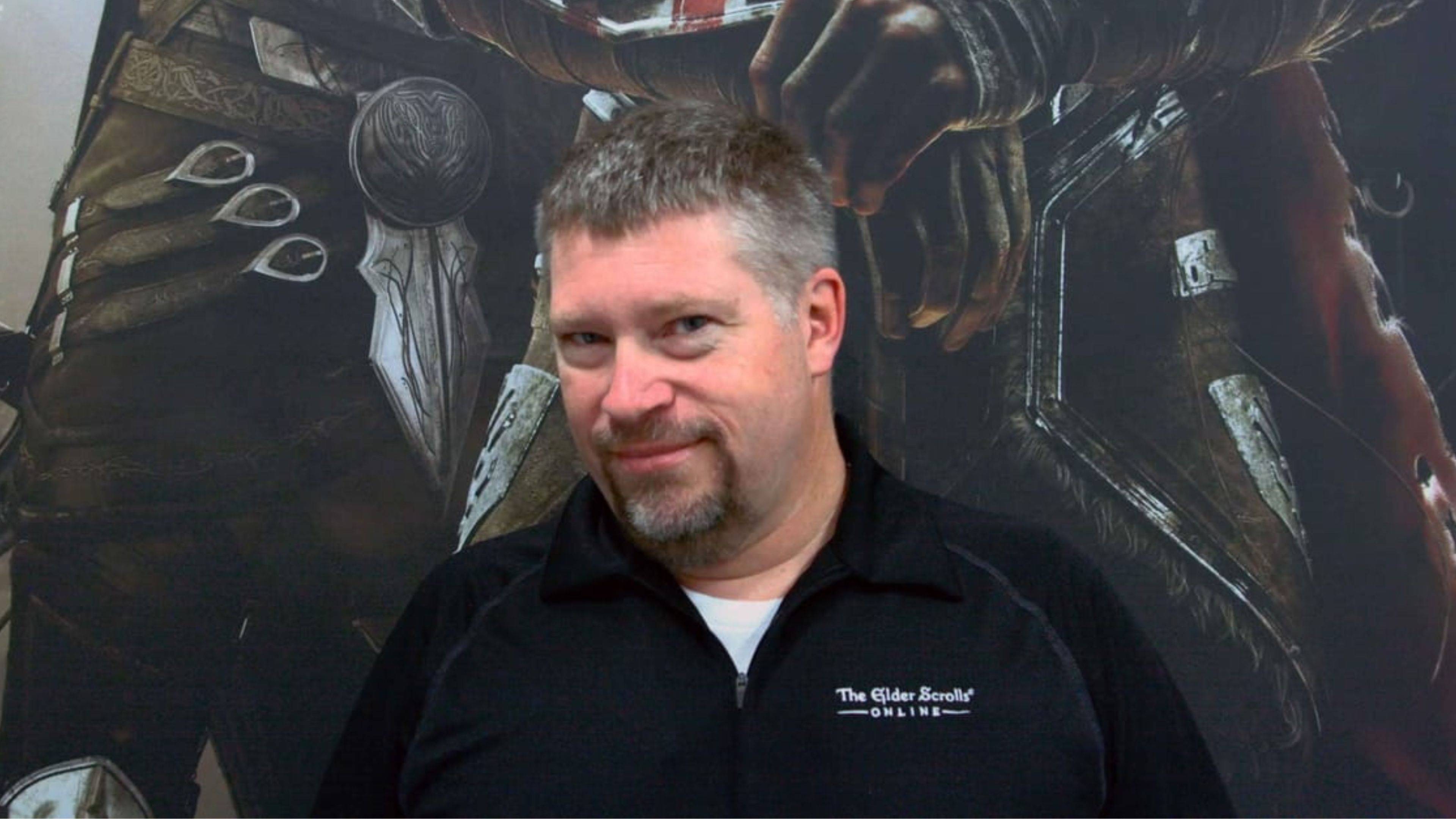 A picture of Zenimax founder Matt Firor in front of an Elder Scrolls Online poster.