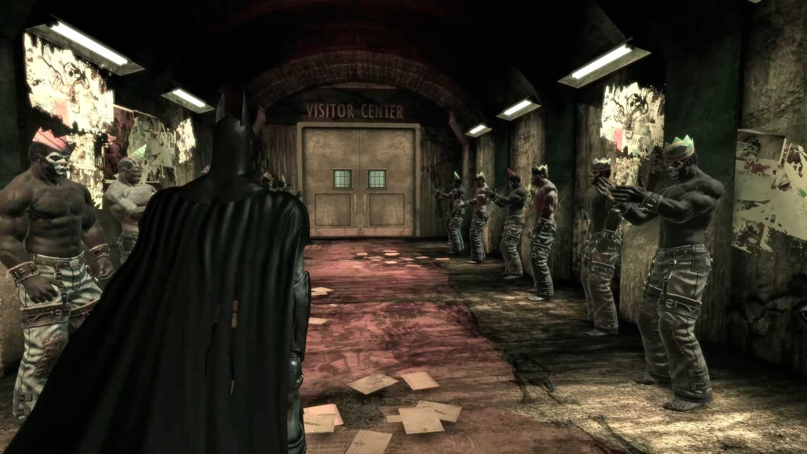 Batman walks into the visitor center with thugs at Arkham Asylum clapping on both sides.