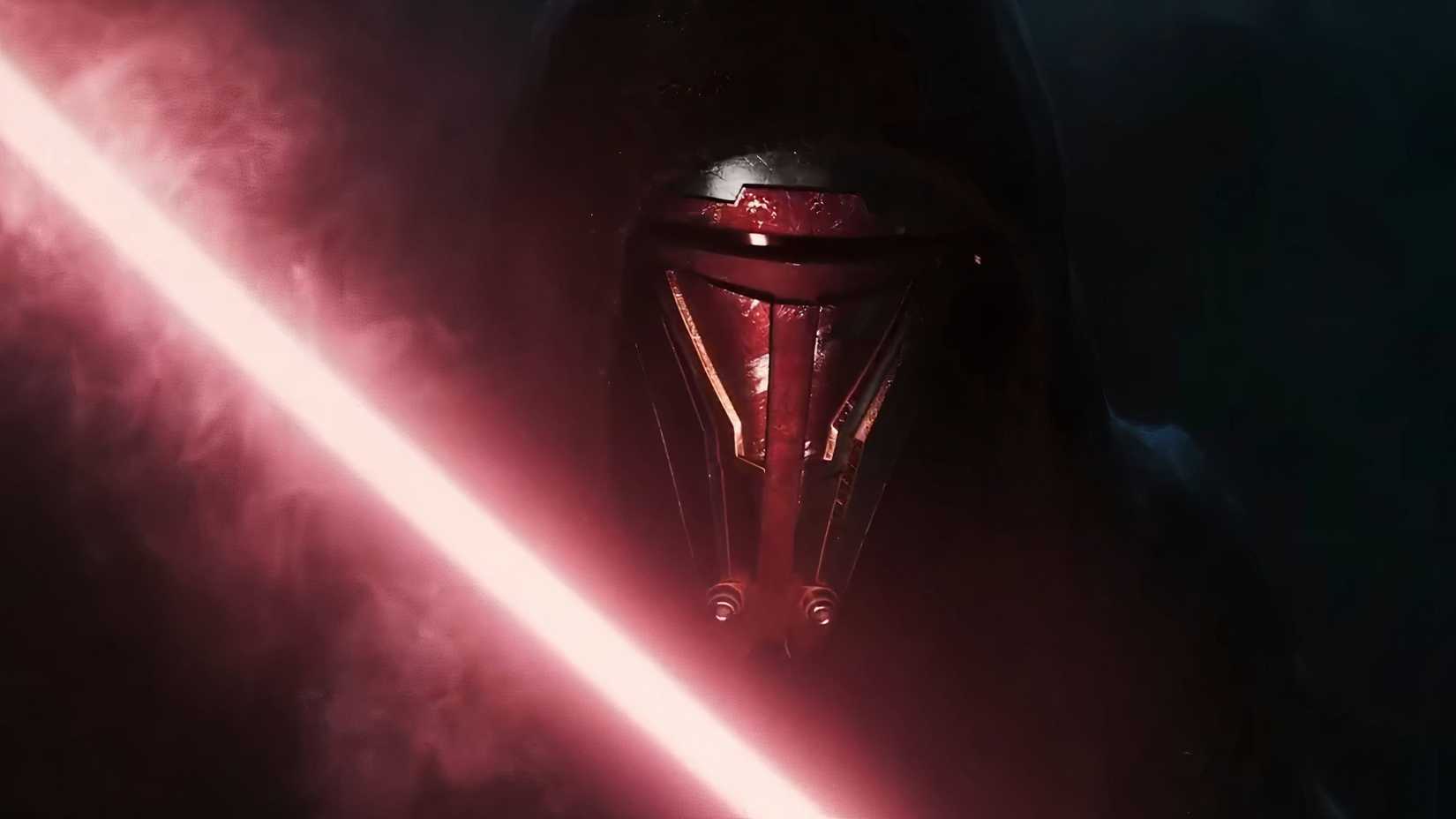 A close up of Revan in the KOTOR remake reveal trailer. They are wearing a mask that covers their entire face, and a black hood. They are also holding a red lightsaber.