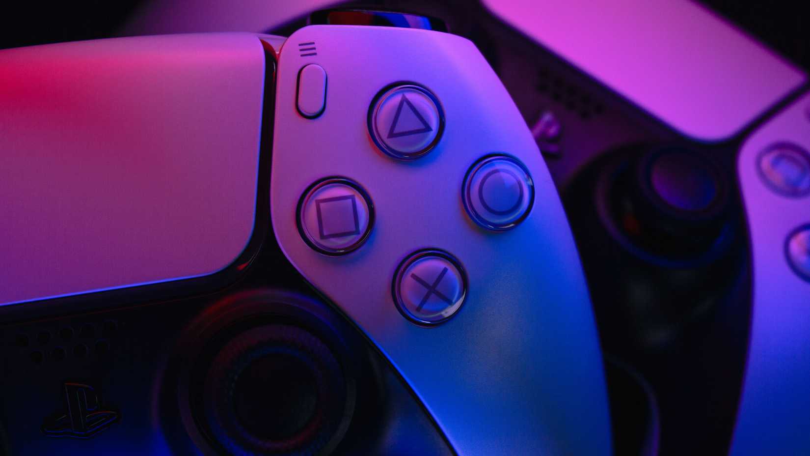 Close-up of two DualSense controllers lit up in blue and purple.