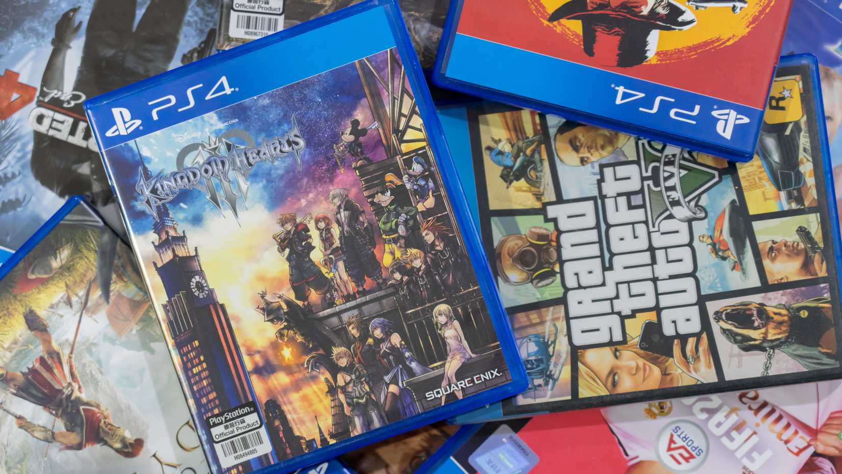 Kingdom Hearts, GTA 5, and other PS4 boxes in a pile.