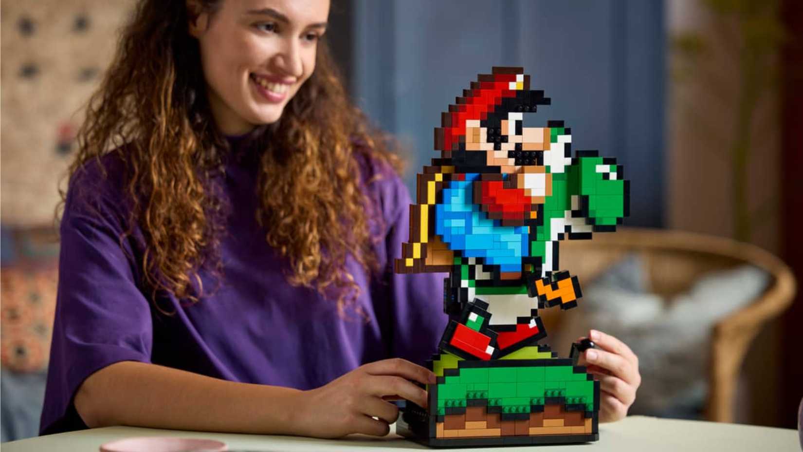 A woman turns the crank on the Super Mario World Mario and Yoshi Lego set.