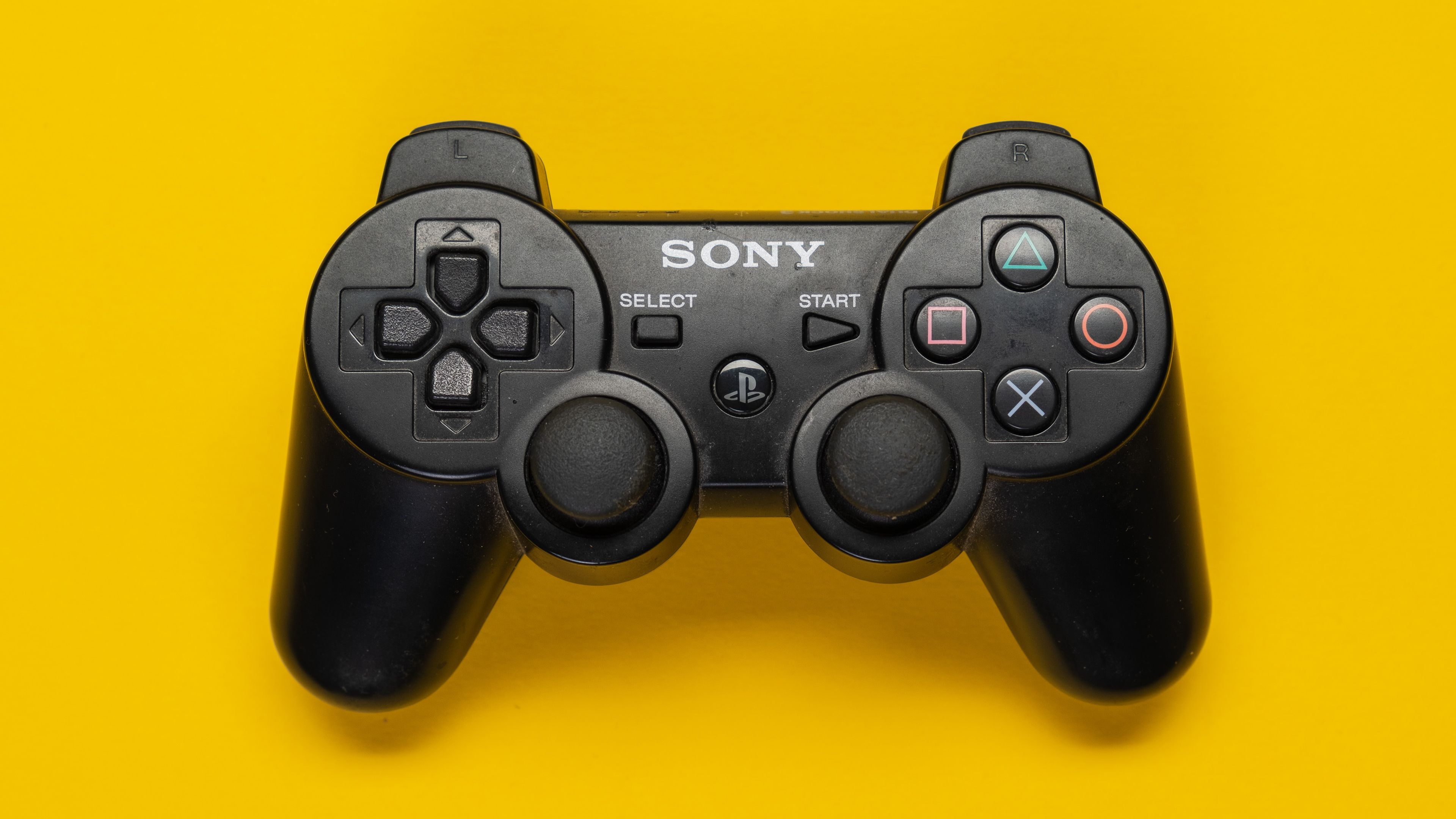 PS3 controller over a yellow background.