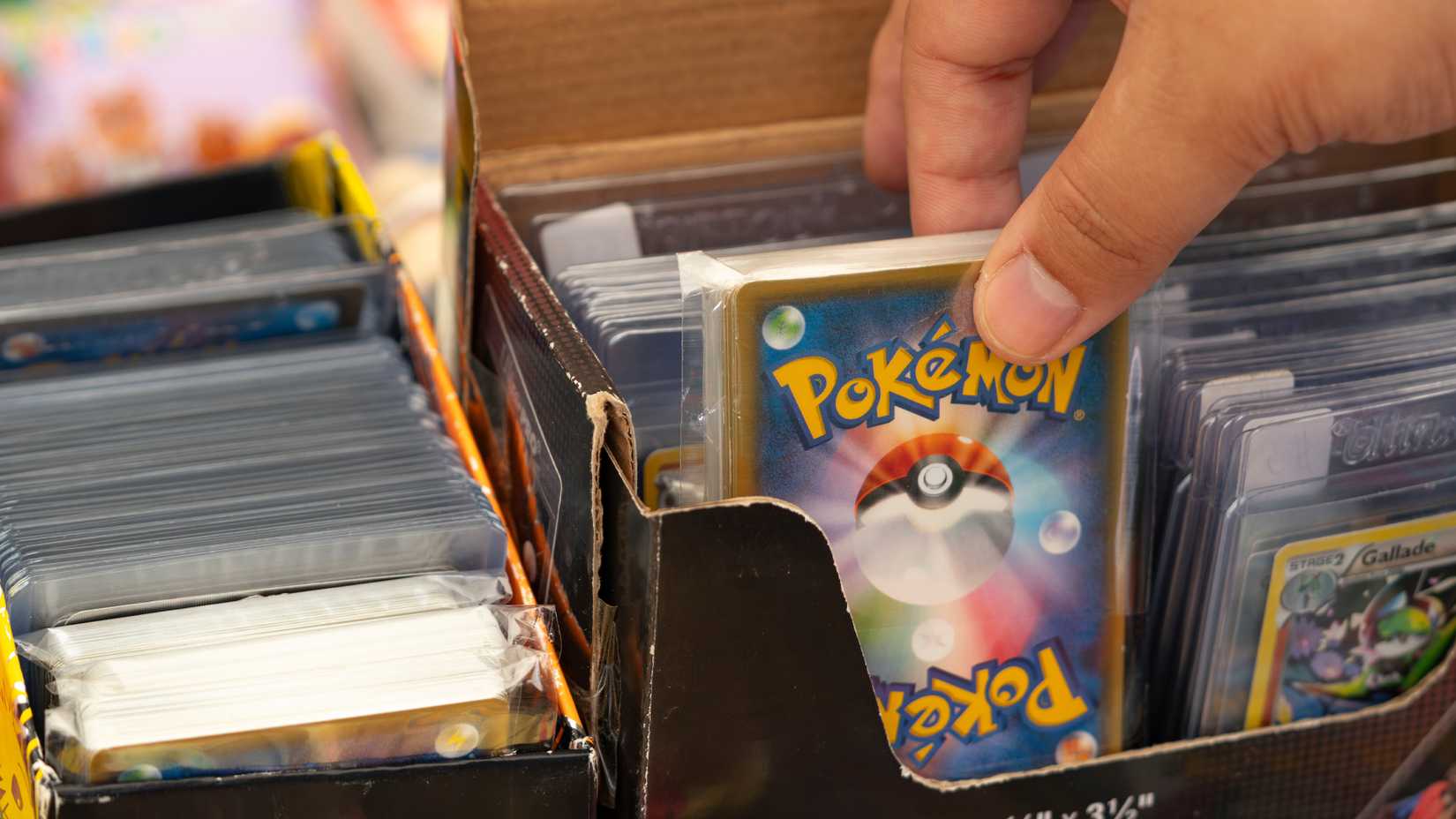 Someone pulling a Pokemon card out of a box.