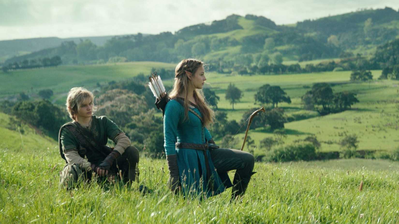 Link and Zelda in the live-action movie crouched and kneeling in a field.