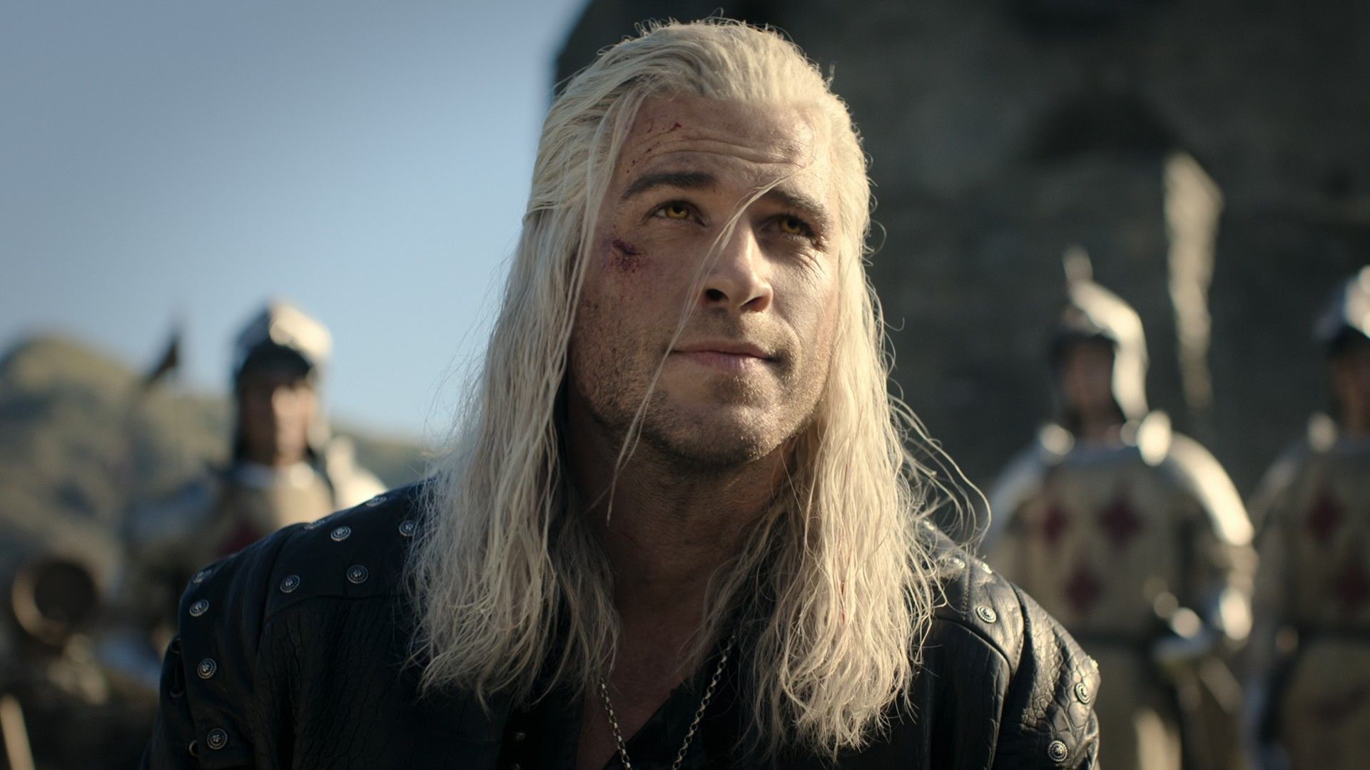 Liam Hemsworth sorri levemente como Geralt na 4ª temporada de The Witcher.