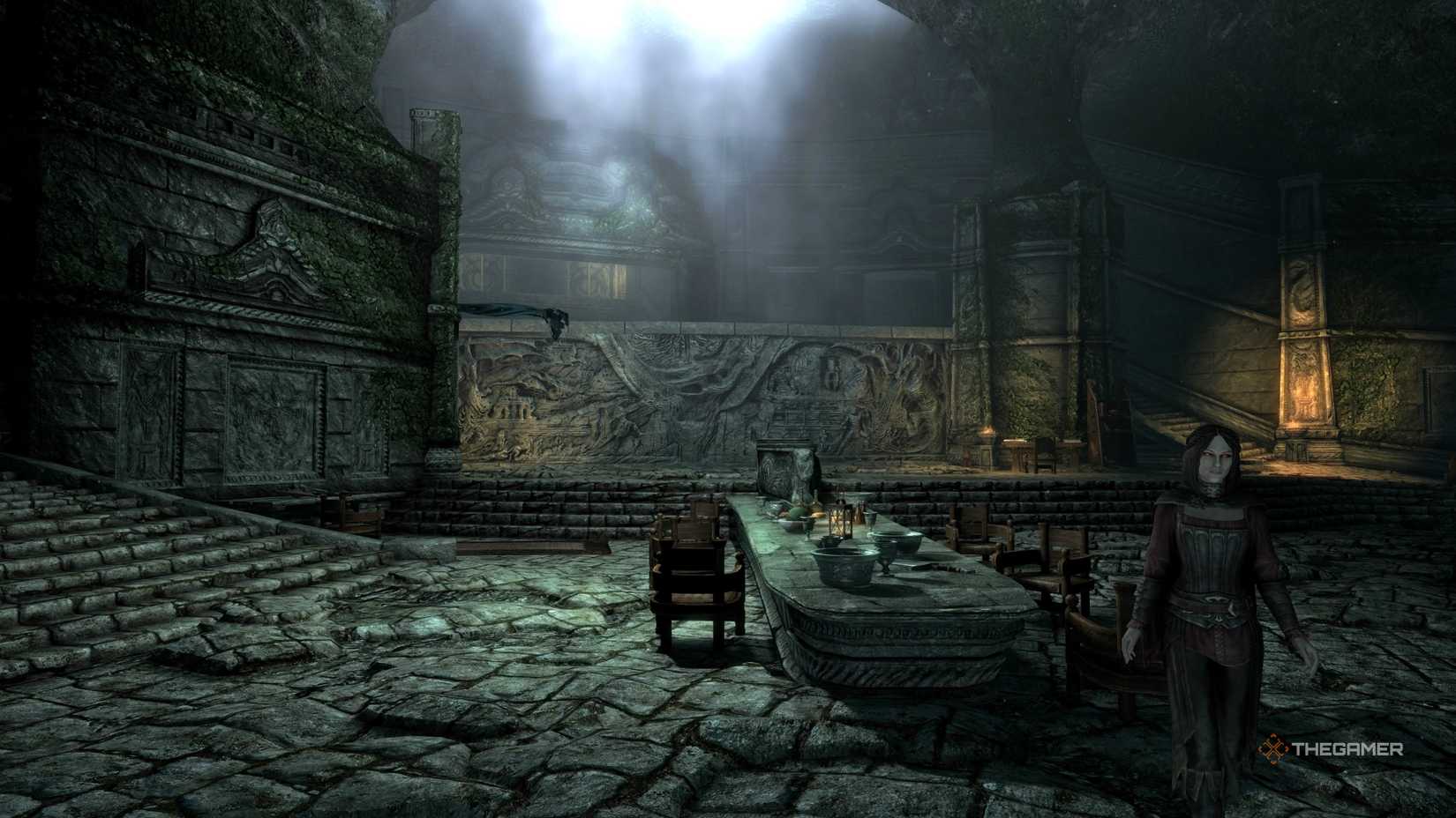 The image showcases Serana as a follower standing in Sky Haven Temple with the player as they are near a long table. Alduin's Wall is visible n the background of the image with low hanging natural light streaming in through the top of the temple with cobblestoned floors throughout.