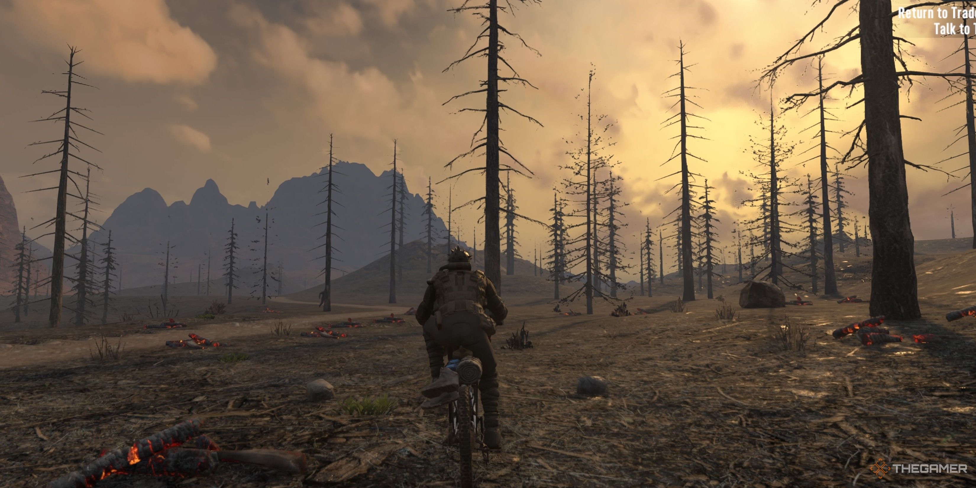 Player character riding a bike as the sun rises in a region full of burnt trees and with no grass in 7 Days To Die.