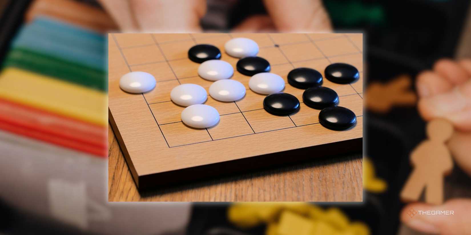 A Go board in front of a blurred image of someone setting up a board game.