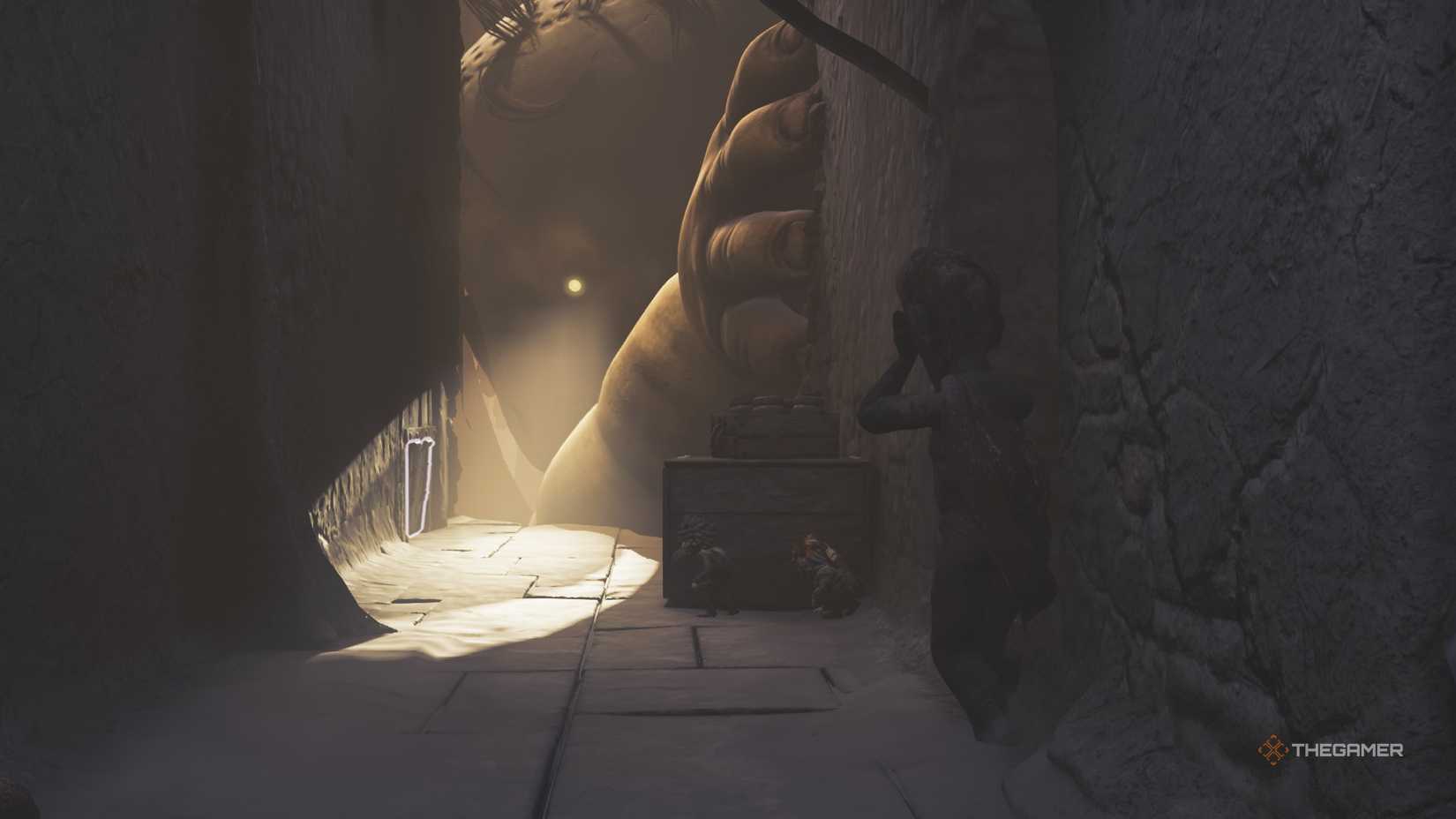 Alone and Low hiding behind a crate while Monster Baby looks for them in Little Nightmares 3.