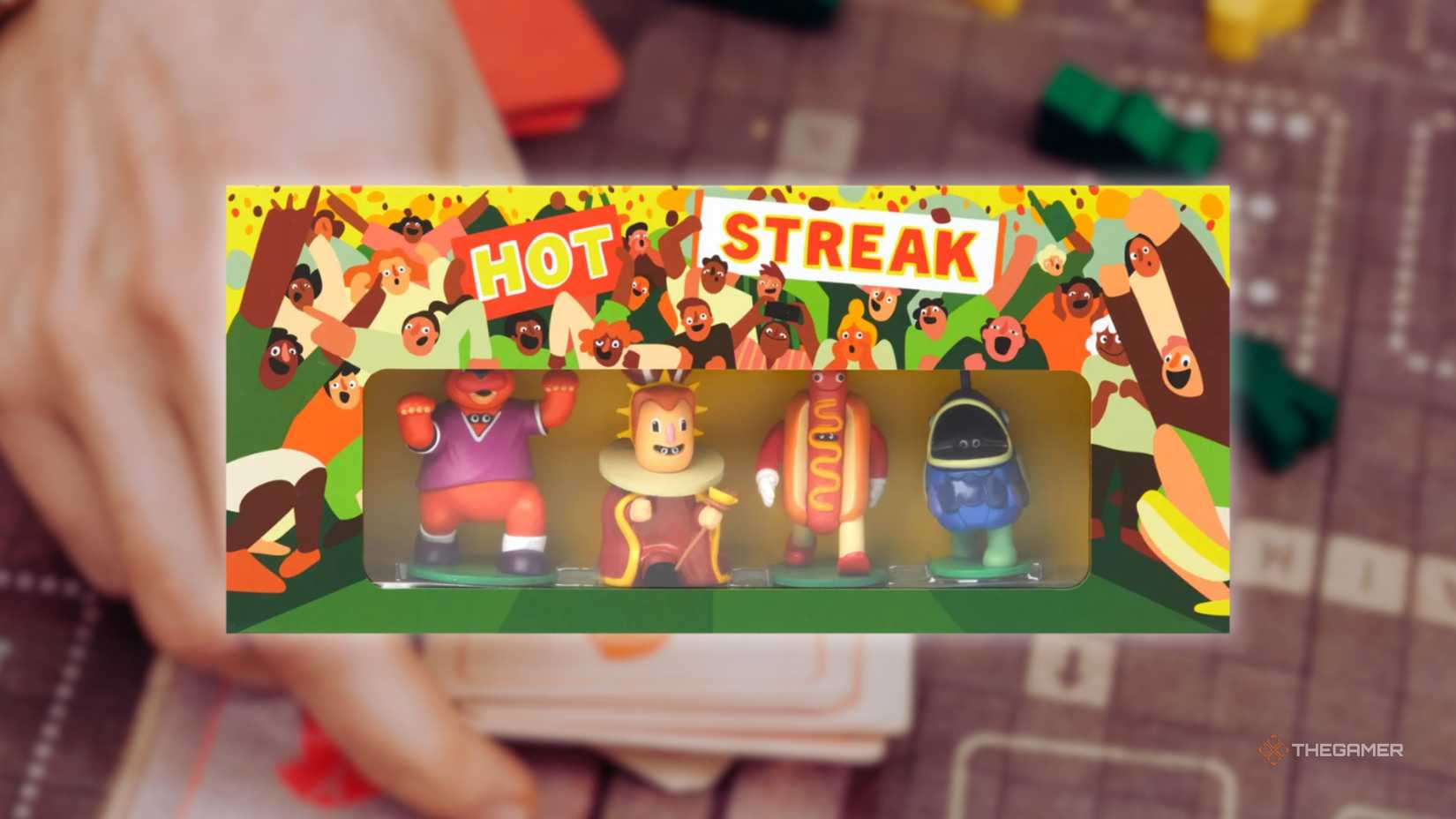 The cover Hot Streak of in front of a hand playing a grid-based board game for the best board games of 2025.