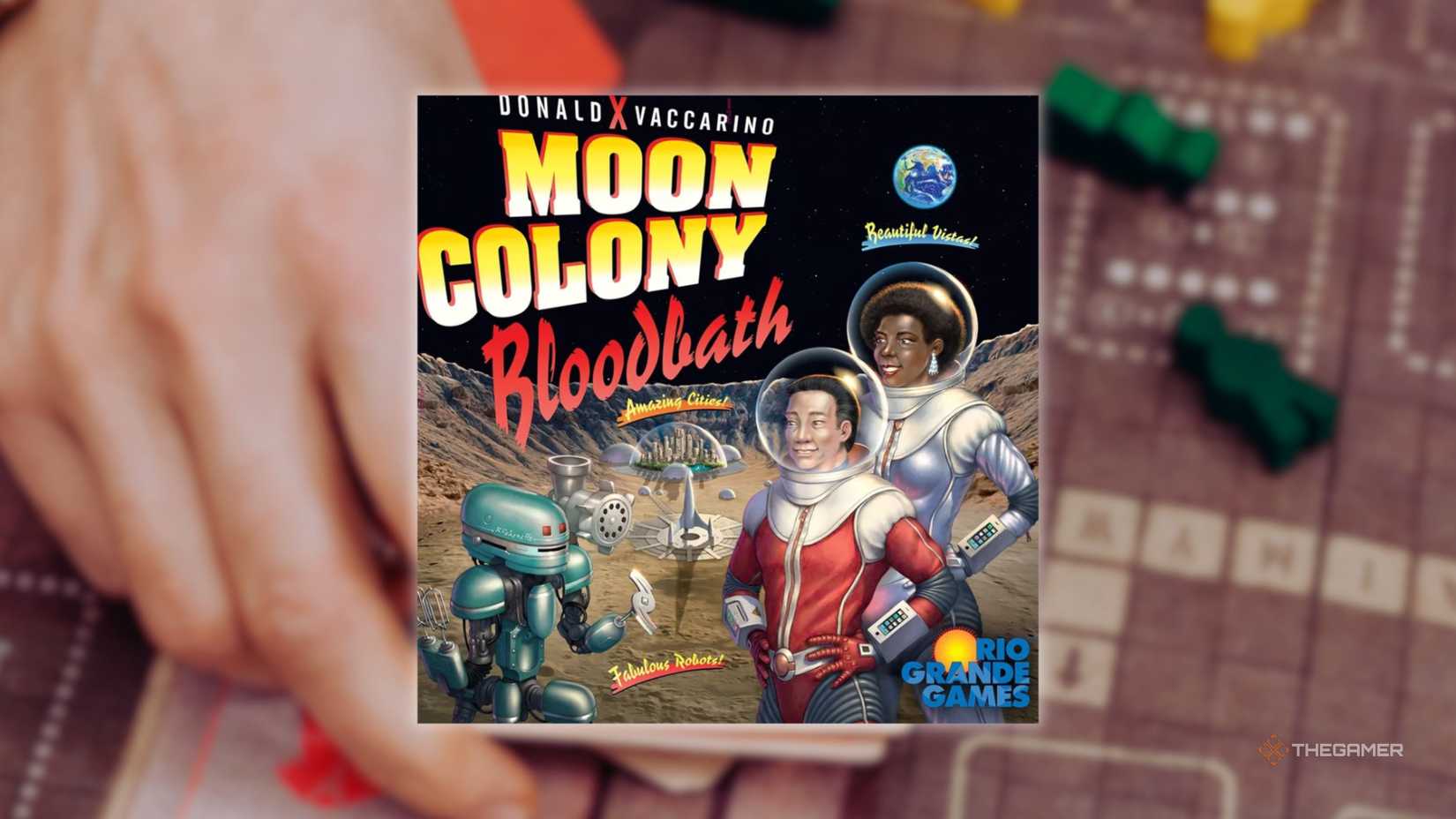 The cover of Moon Colony Bloodbath in front of a hand playing a grid-based board game for the best board games of 2025.