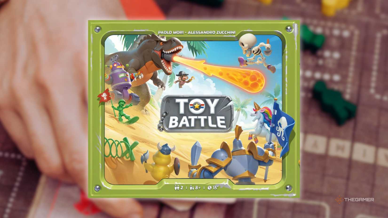 The cover of Toy Battle in front of a hand playing a grid-based board game for the best board games of 2025.