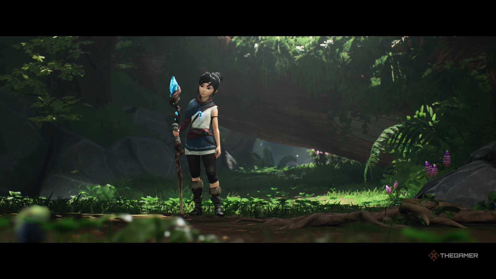 Kena: Kena standing in the forest holding a staff in Bridge of Spirits.