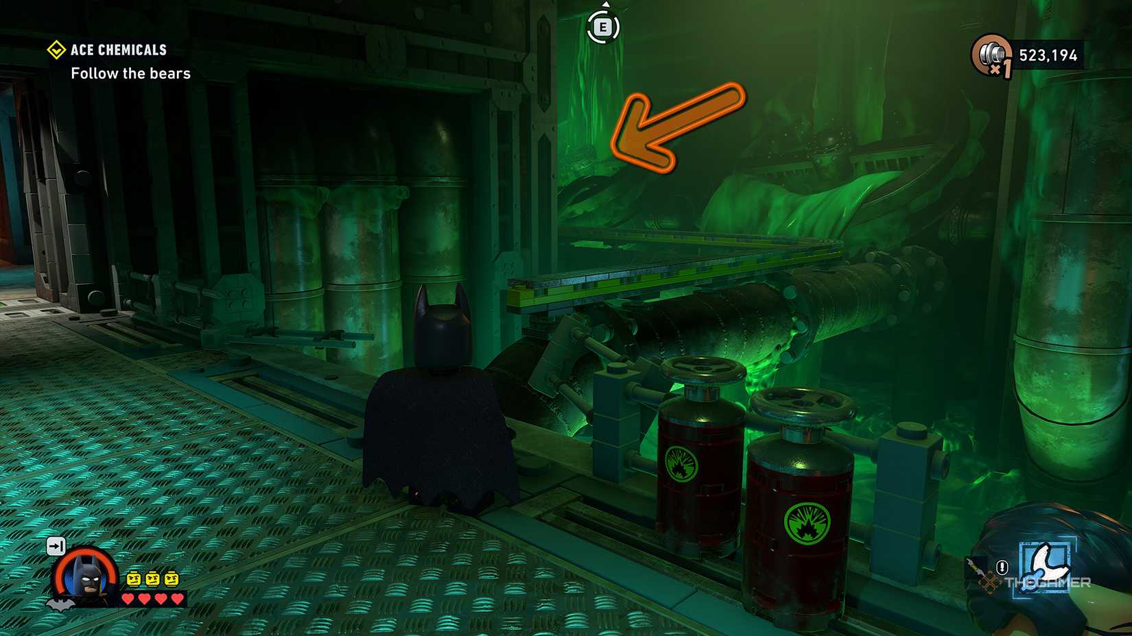 Batman standing on a broken ledge with an orange arrow pointing to the corner from Lego Batman The Dark Knight Legacy.