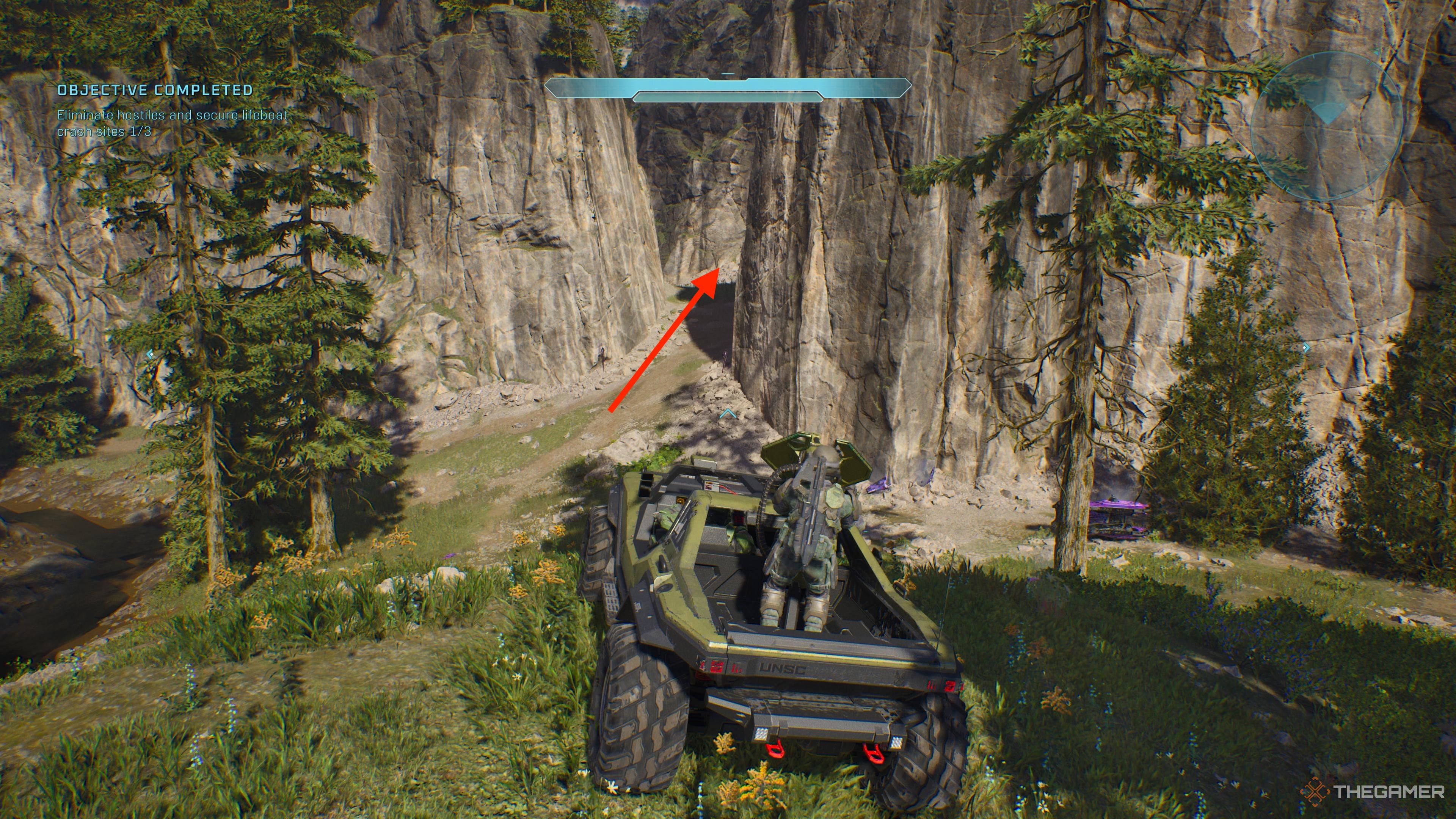Warthog sitting in the middle of a field with an arrow pointing toward a canyon path in Halo: Campaign Evolved.
