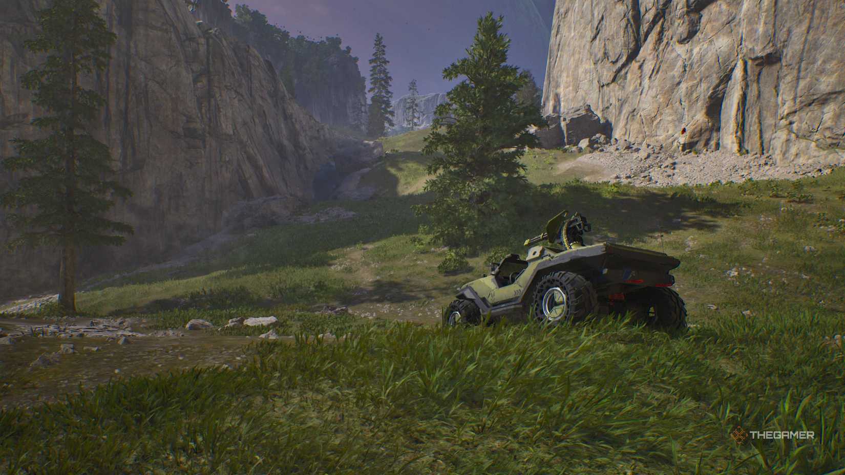 A warthog vehicle sitting in some grass with rocky cliffs and trees in the distance behind it in Halo: Campaign Evolved.